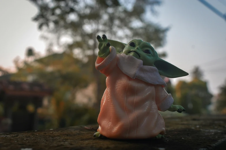 a toy of baby yoda standing on top of a wall