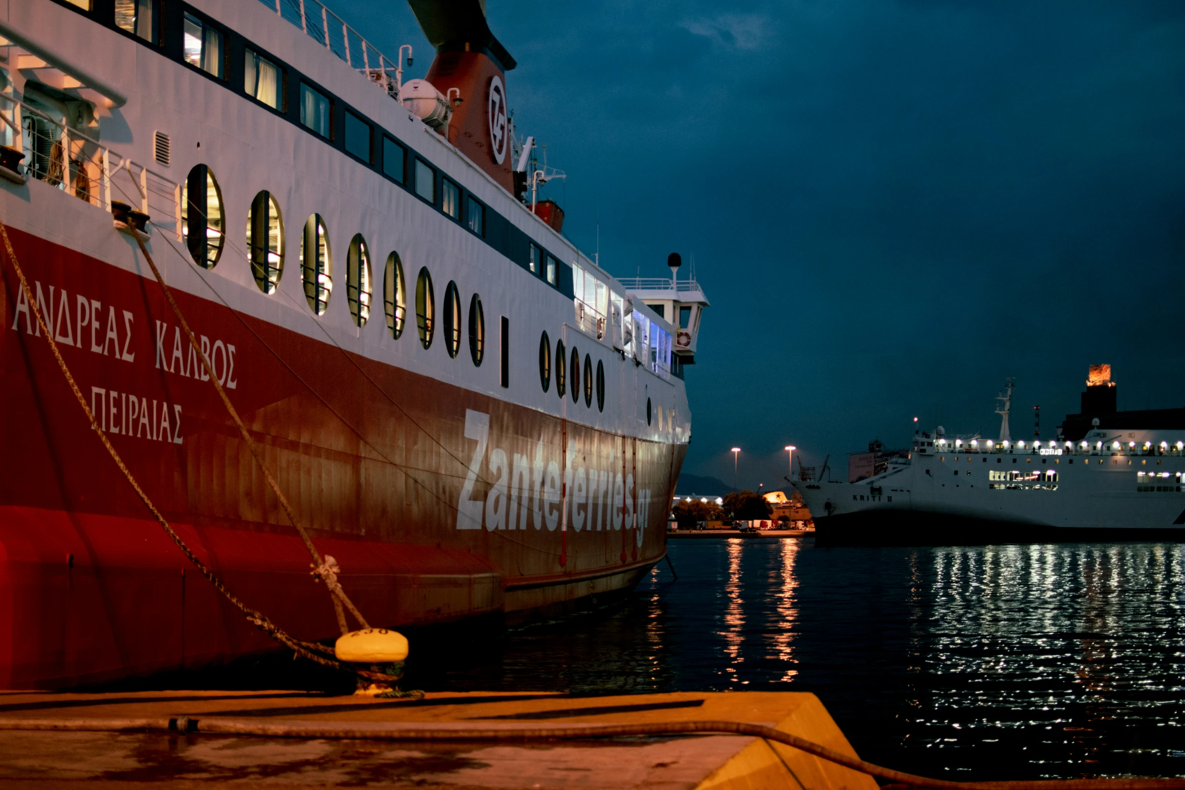 an cruise ship docked at night with another large boat nearby