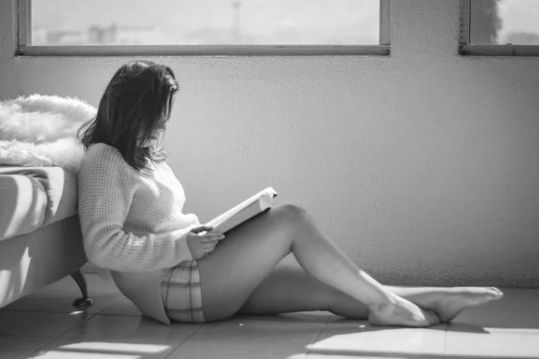 a woman in underwear sits on the floor and reads