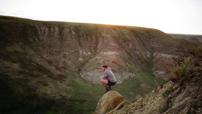 a man on top of a cliff while standing up in the dirt