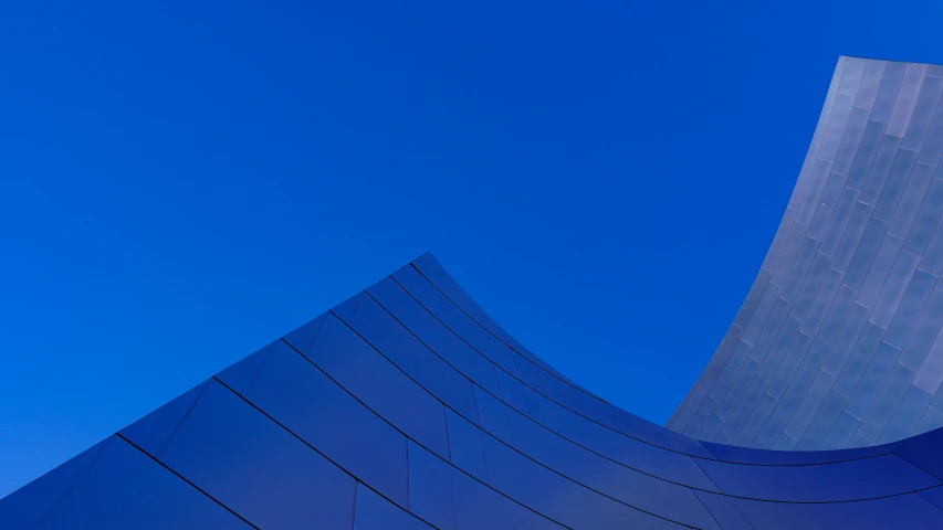 a blue building with a very tall curve next to it