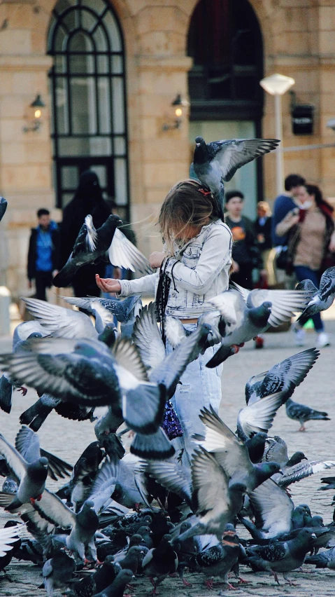 a woman feeding birds in front of a building