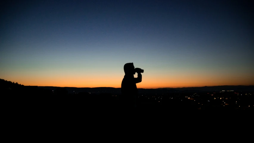 a person holds an object over their head during sunset