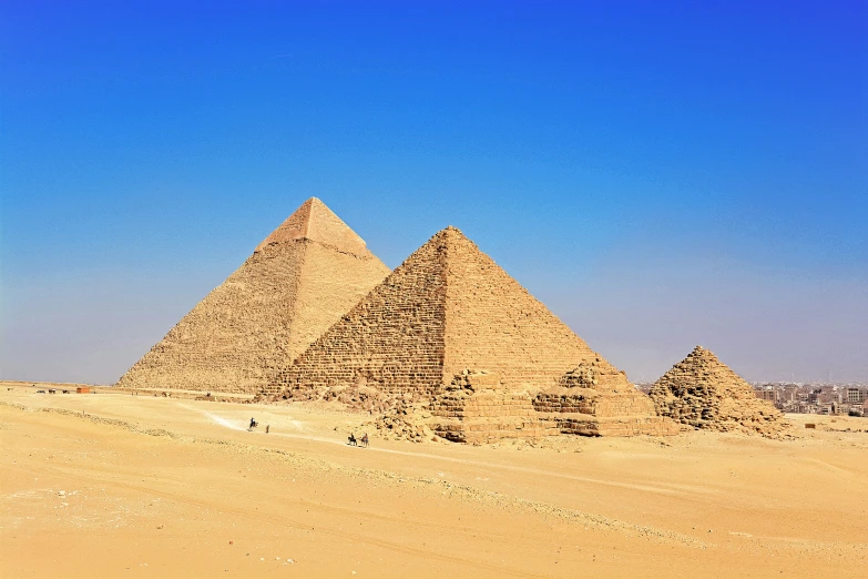 two pyramids in the desert under blue skies