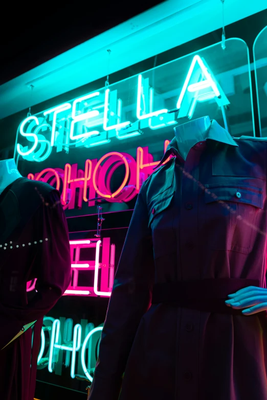 a neon light behind two mannequins dressed in clothes