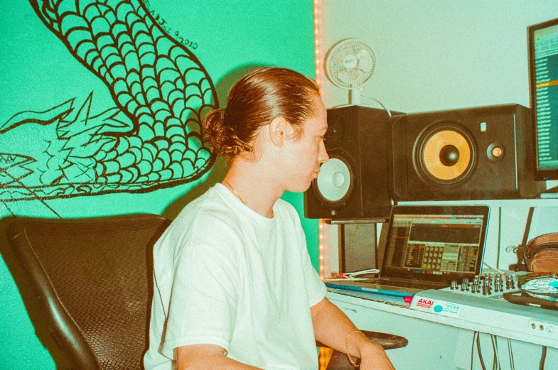 a young man plays on a keyboard in front of some computer equipment