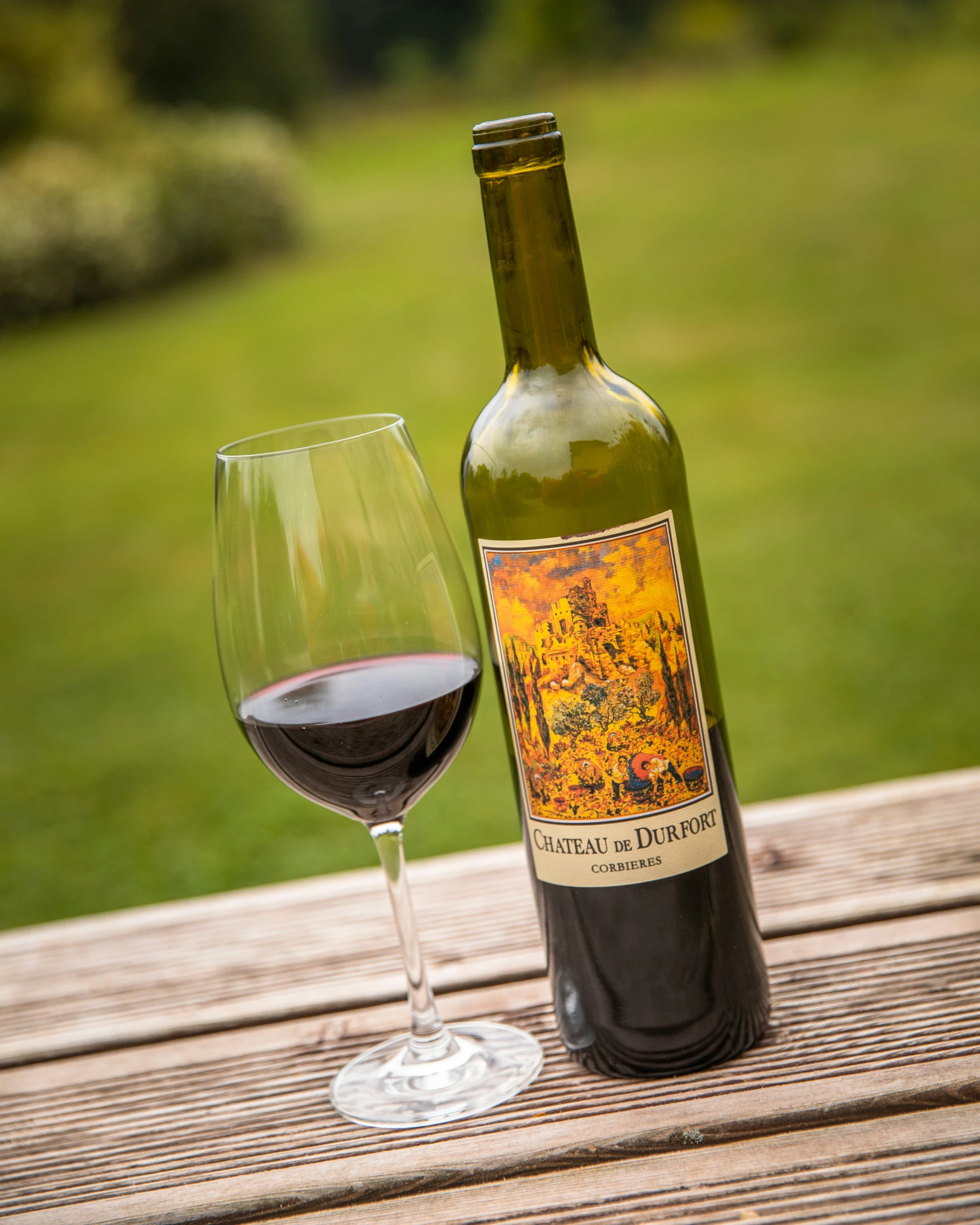 a wine bottle next to a glass with a red drink on it