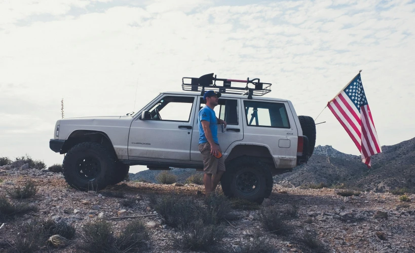 a man stands by his pickup truck with a flag on the side