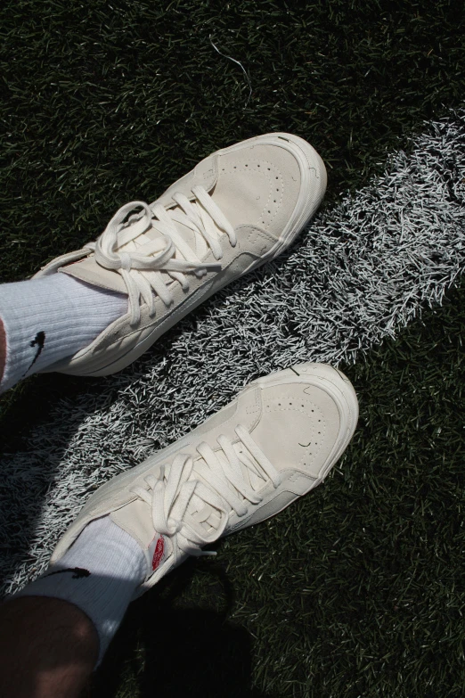 a persons foot and white tennis shoe on grass