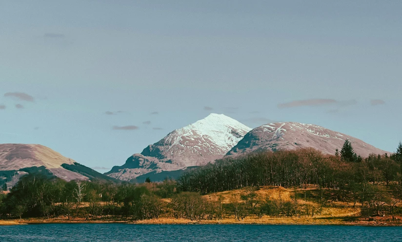 the mountains are shown against the water and blue sky