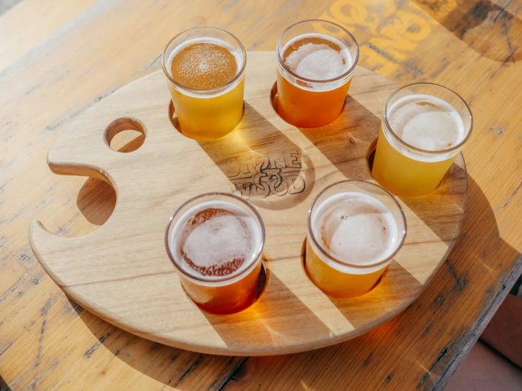 four glasses are next to each other on a circular wooden tray