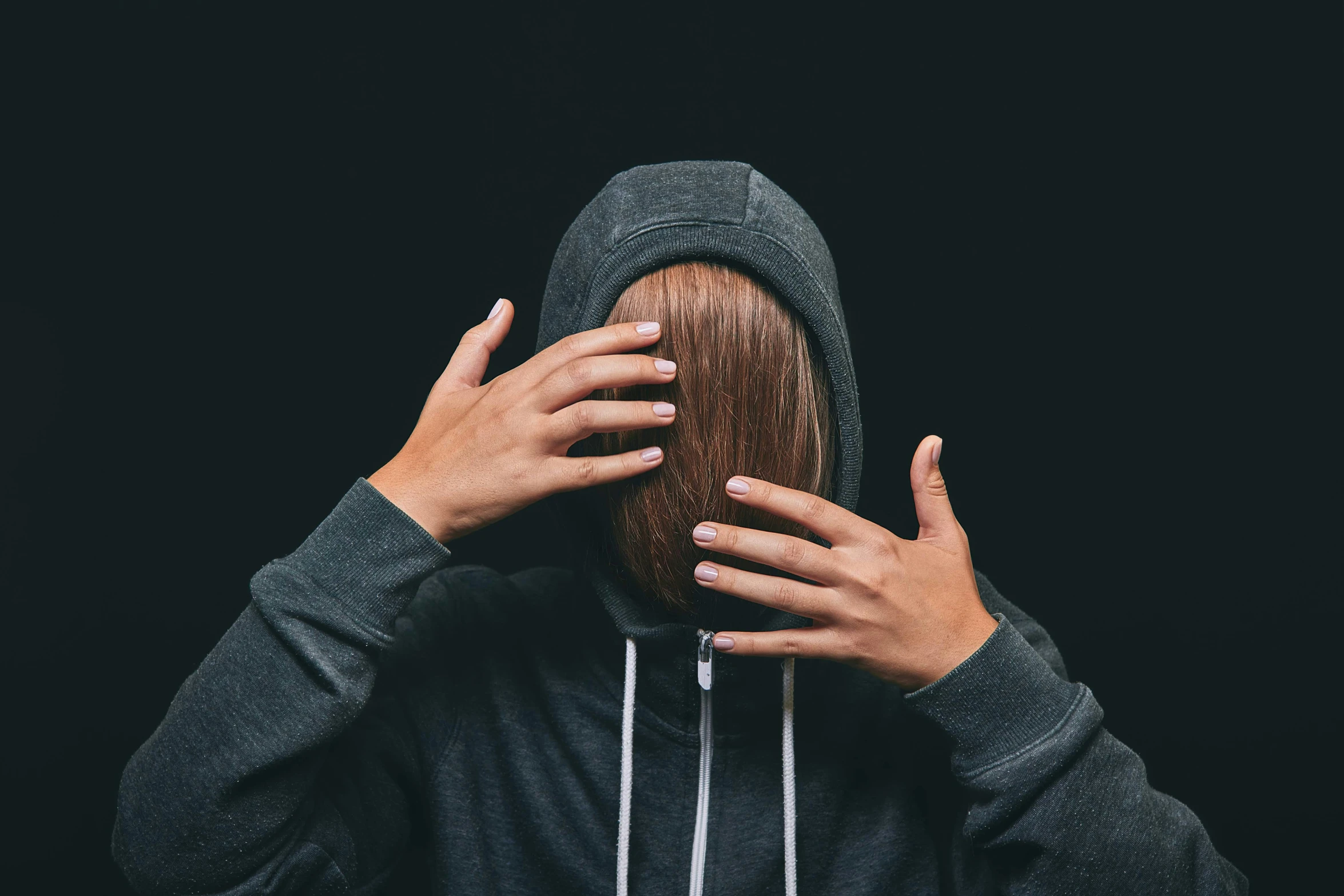 woman covering her face with her hands, while covering her hair