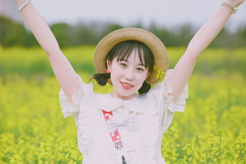 a woman standing in the middle of a green field with her arms up