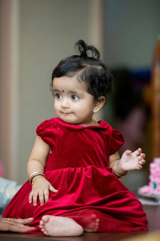 a  wearing a red dress looks out from a table