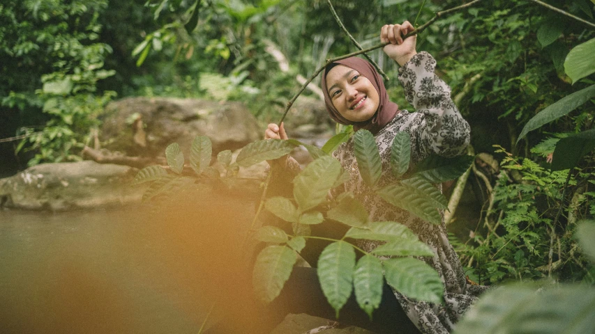 a woman smiles for the camera while standing among foliage