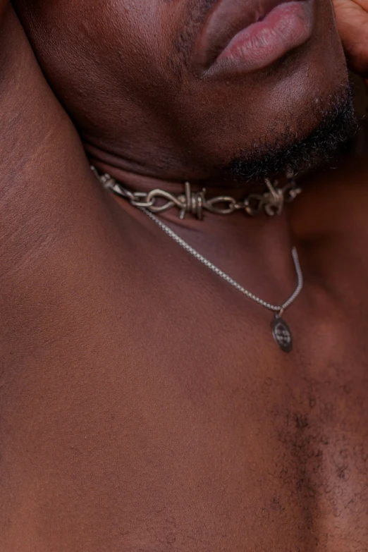 a man wearing a chain on his neck looks straight ahead