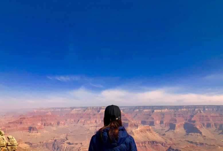 the man is standing on top of the mountain, looking at the mountains