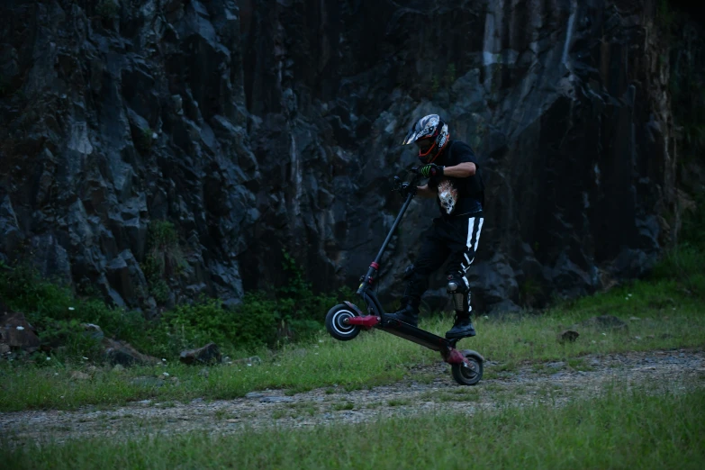 a man with a helmet, knee pads and goggles, is rollerblading on a mountain trail