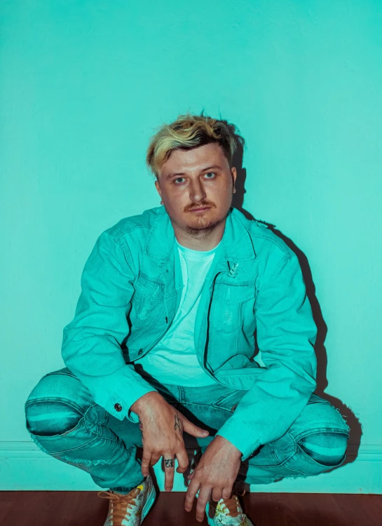 a man sitting in front of a blue wall with shoes