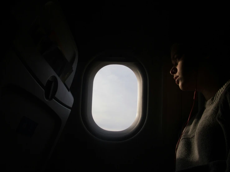 woman sitting on plane seat in front of window with cloudy sky