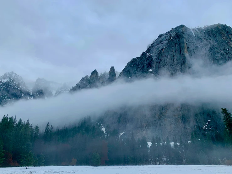 a snow covered mountain with a lot of low hanging clouds