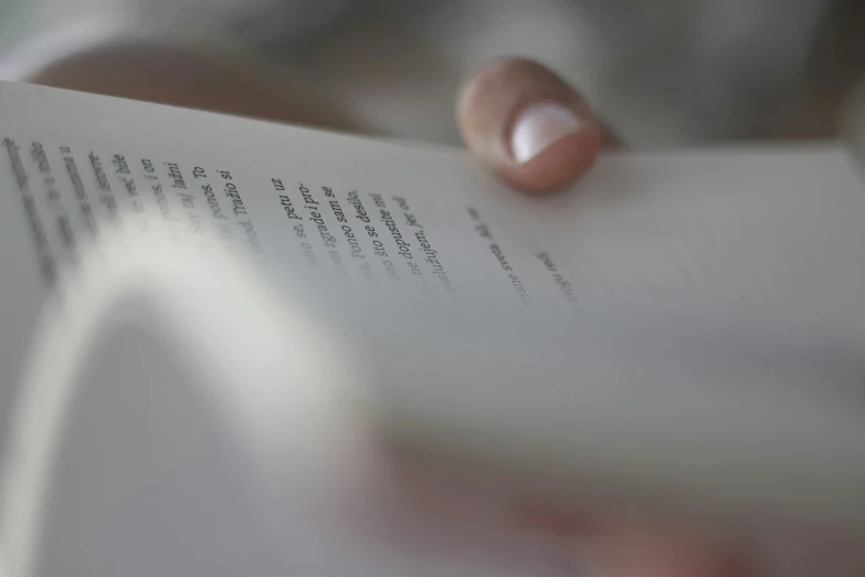 a person holds out an open book, with a blurry background