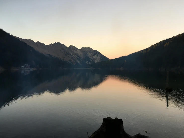 a mountain range on the shore of a lake during sunrise