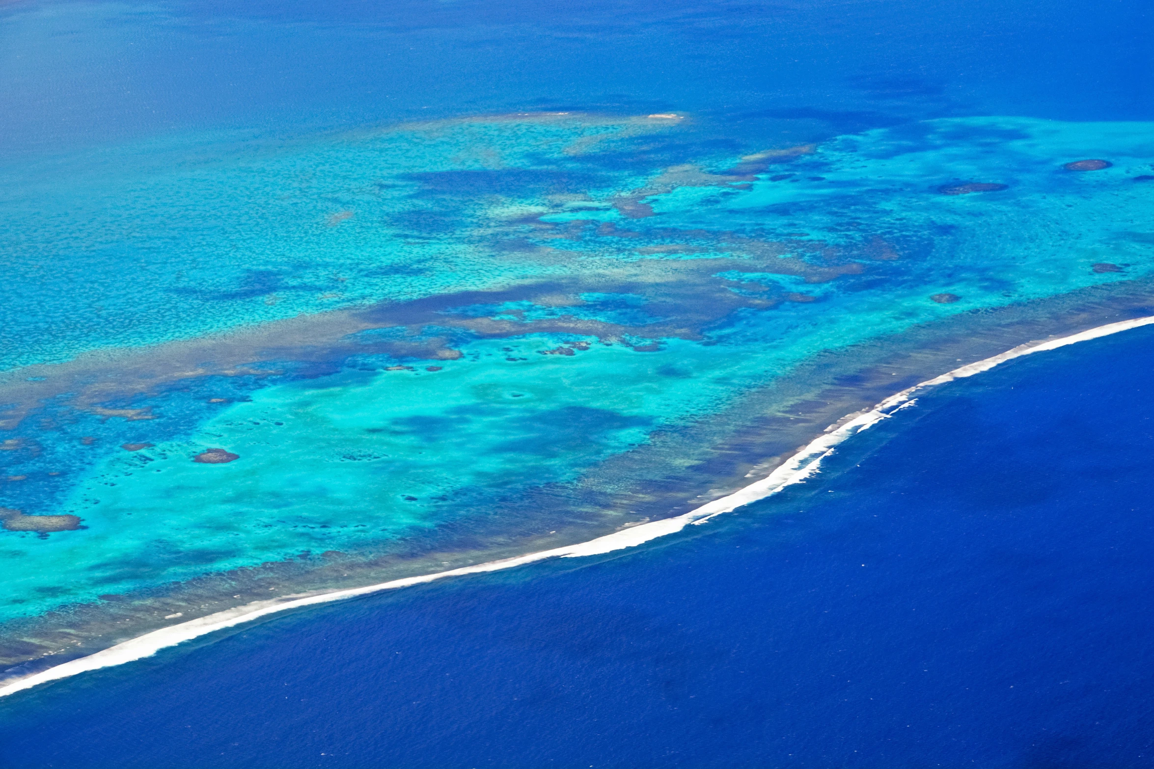 an aerial view of the coral reef on the edge of a large body of water