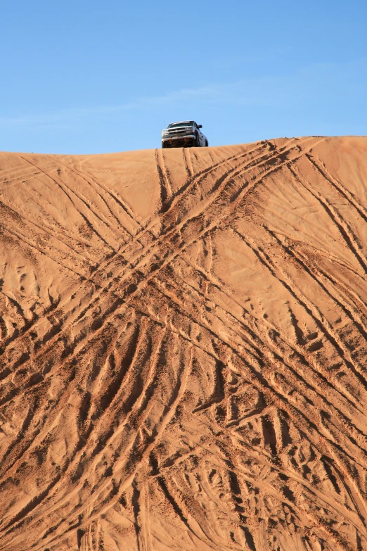 a suv in the sand making a trail