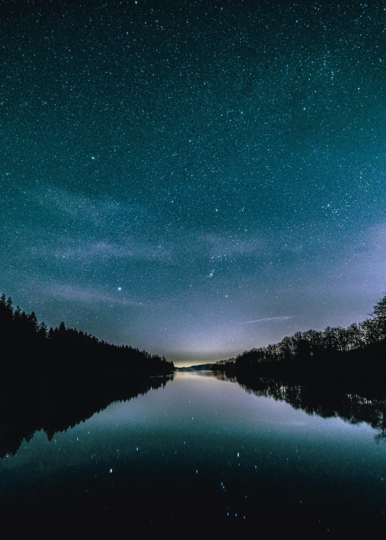 a lake in the middle of the night with the stars above it