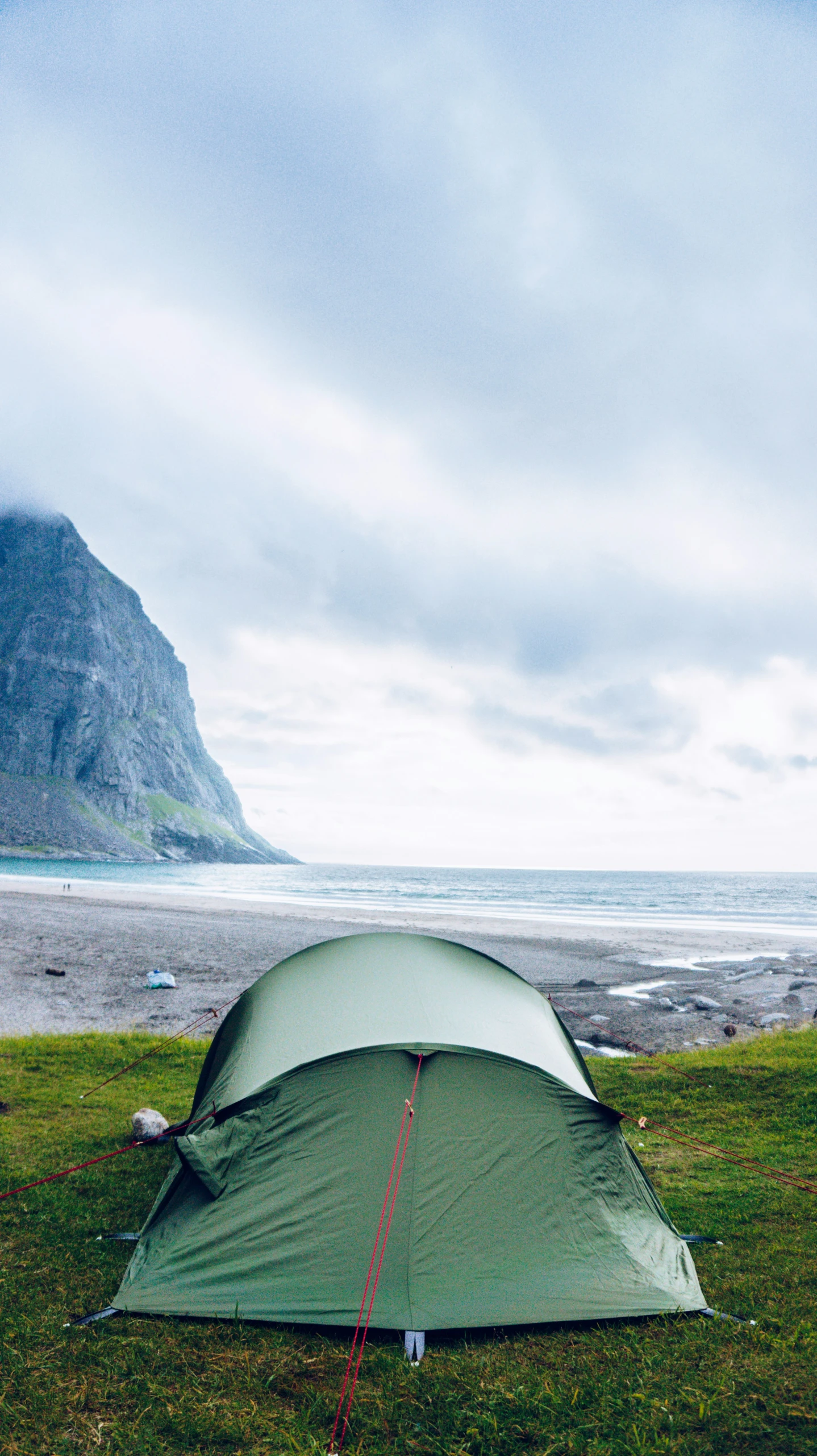 a camping tent pitched up on the beach next to some mountains