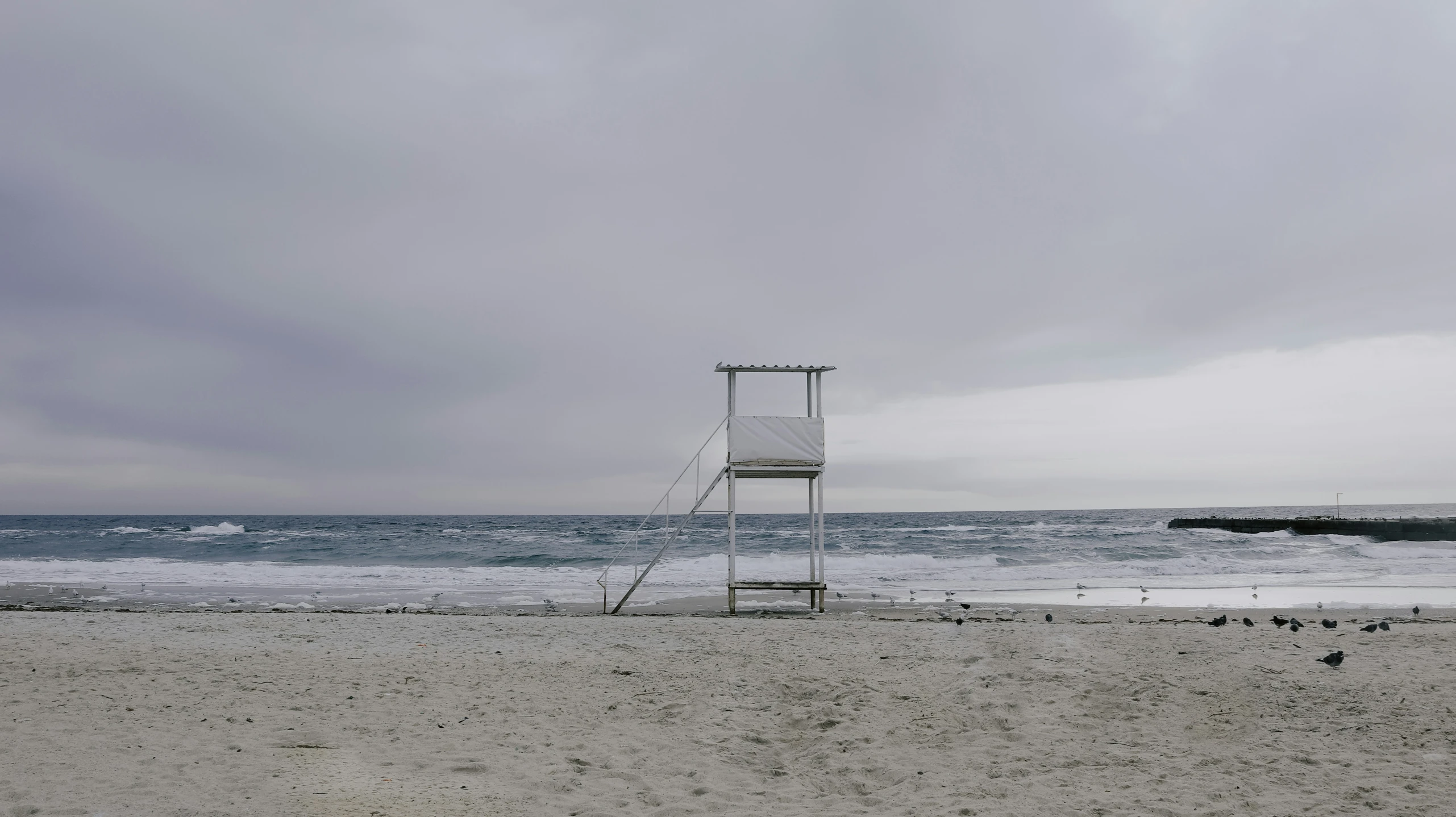 a life guard stand near the ocean under a cloudy sky