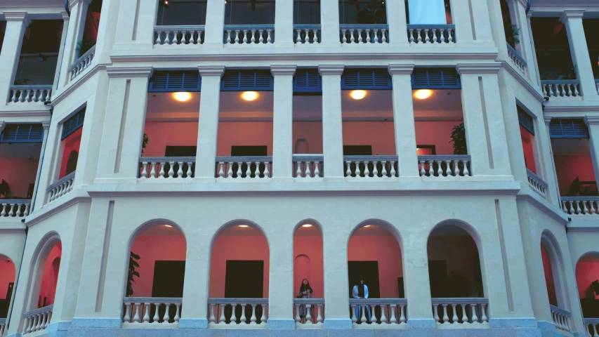 two people stand on the balconies outside of a multi - story building