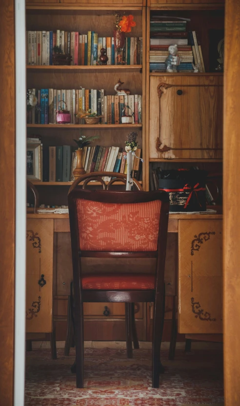 an old office with a red chair and a shelf full of books