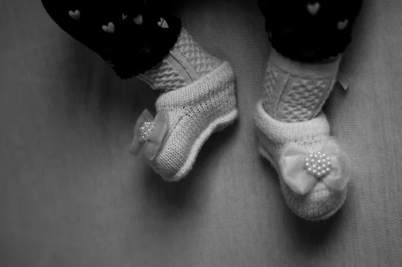 a pair of feet with white knitted slippers on