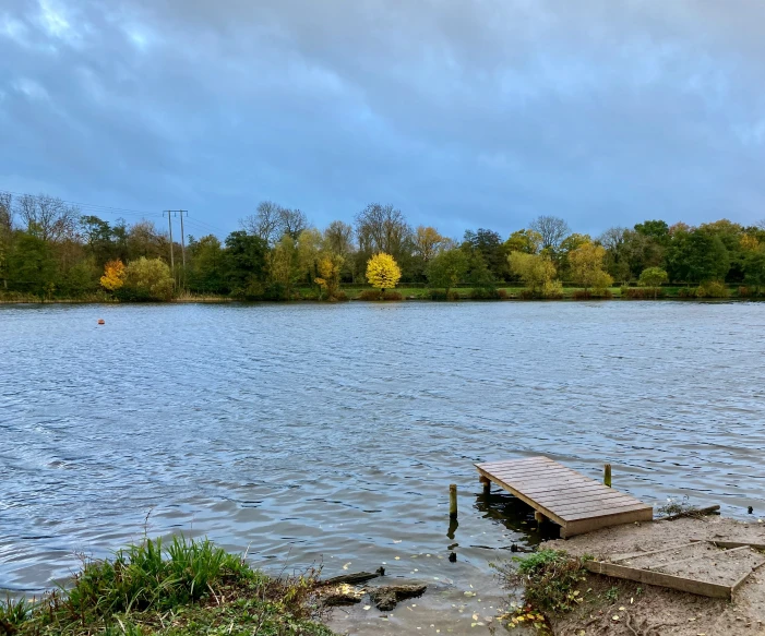 a dock on the edge of a lake with a building in the background