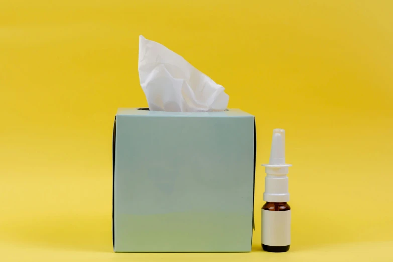 a tissue and bottle of toothpaste on a yellow background