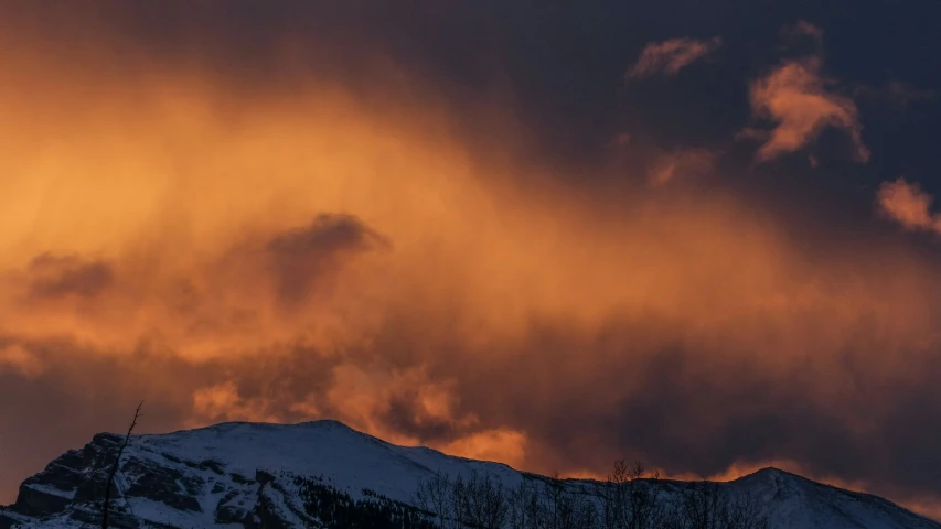 the sun sets behind a mountain covered in snow