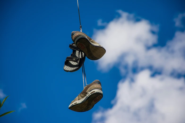 shoes dangling from a string are seen against the blue sky