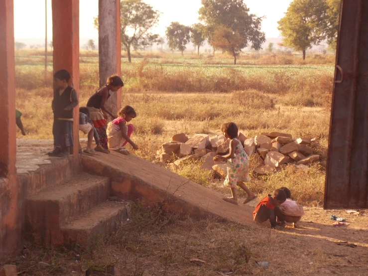 three children play in front of an abandoned building