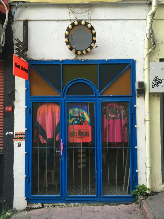 storefront with glass door and neon colored clothes behind a mirror