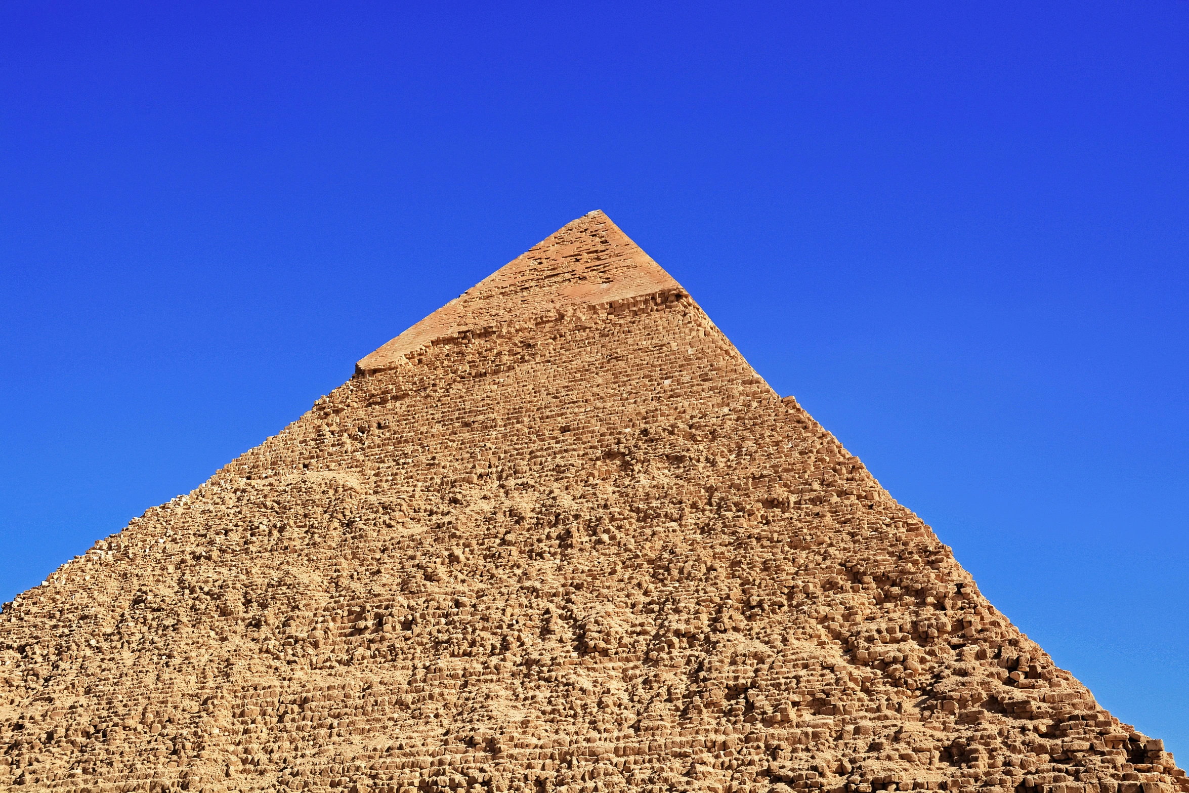 a very large, ancient egyptian pyramid with blue sky behind it