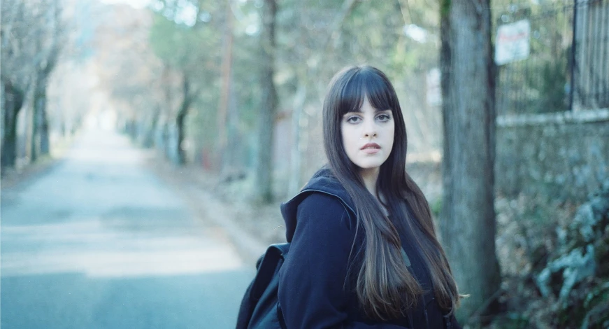 the girl with long dark hair is standing in the street