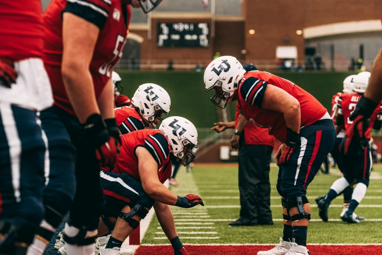 several football players kneel down and talk to an official