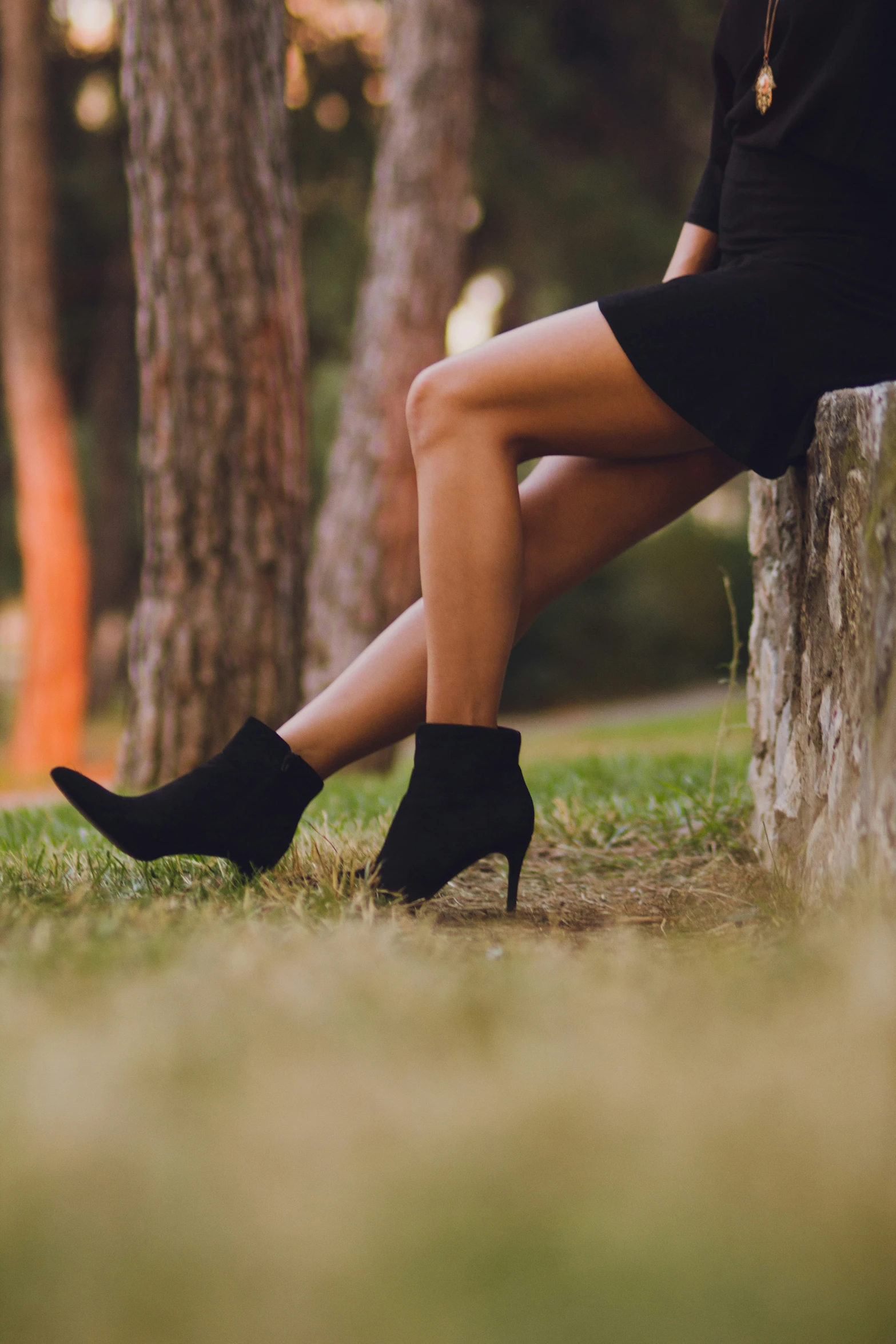 a woman sits on a stone bench in a grassy area