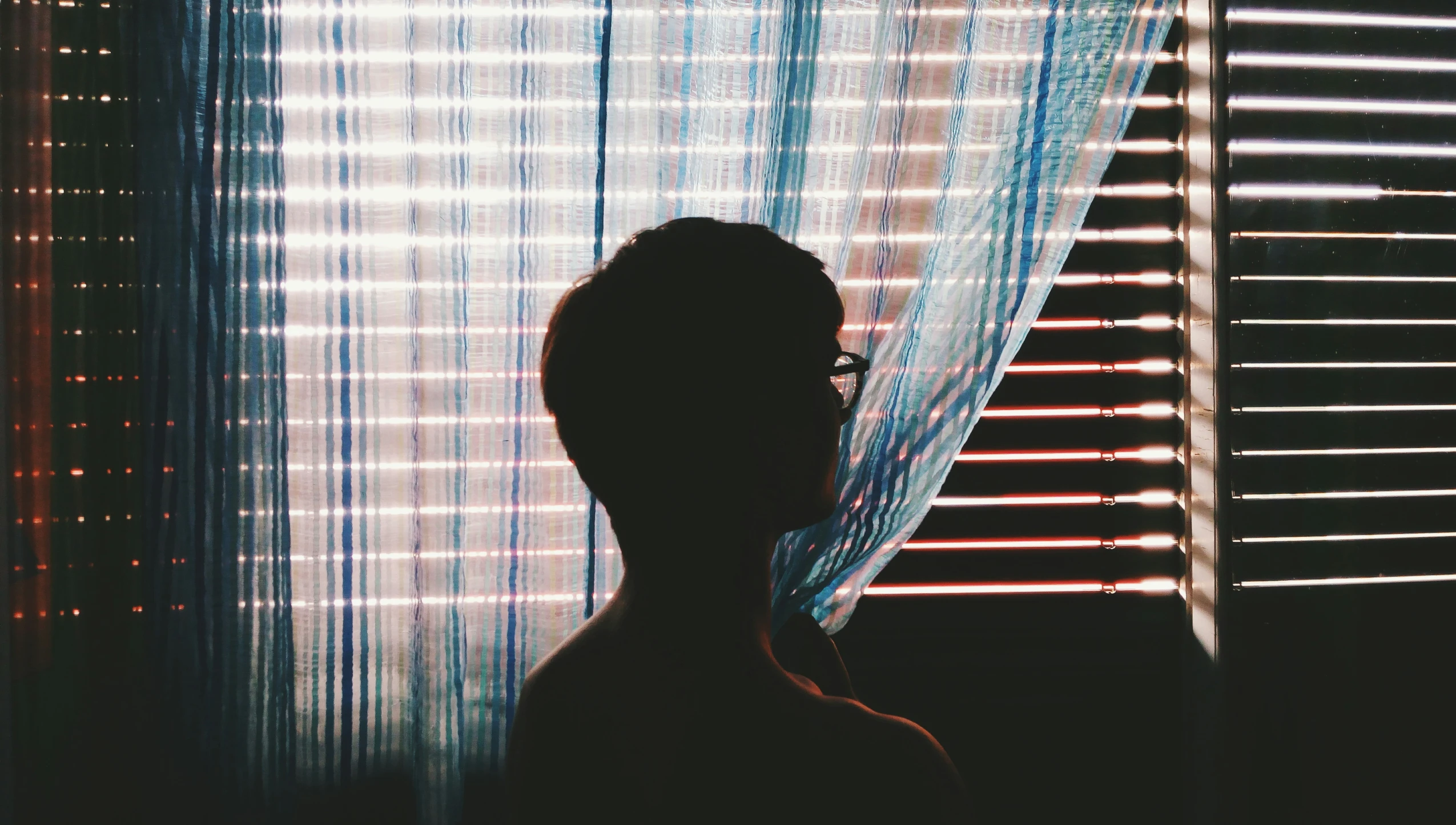 a woman stands near a window with colored curtains