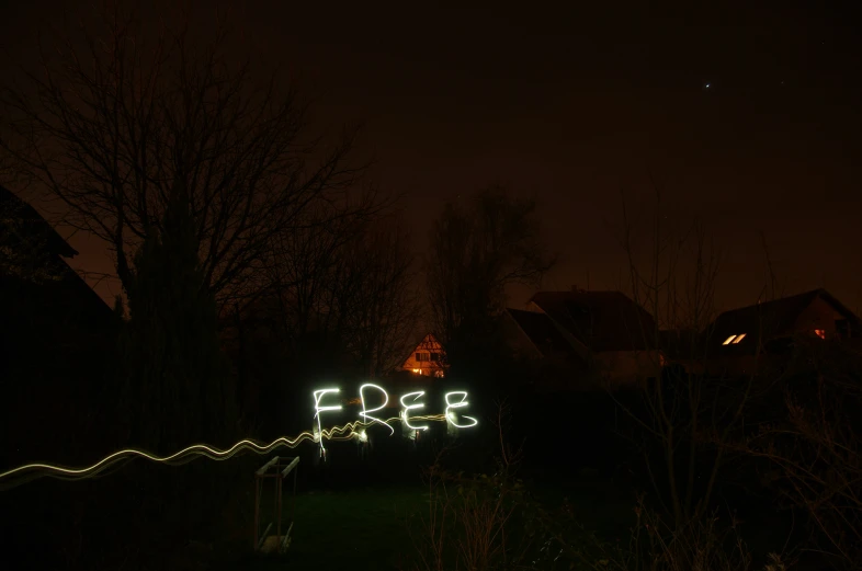 a lit up sign reads free and in front of some trees