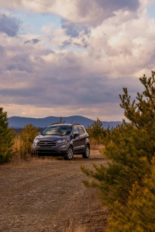 a grey suv parked on top of a dirt field