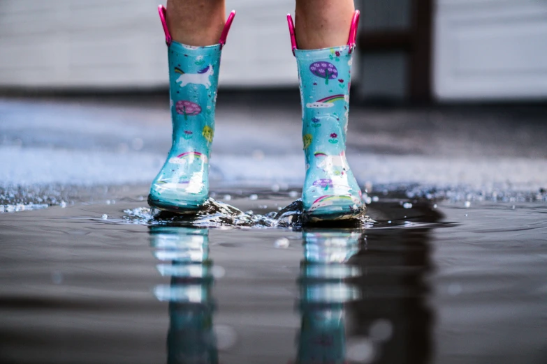 a person wearing blue rain boots standing on wet ground