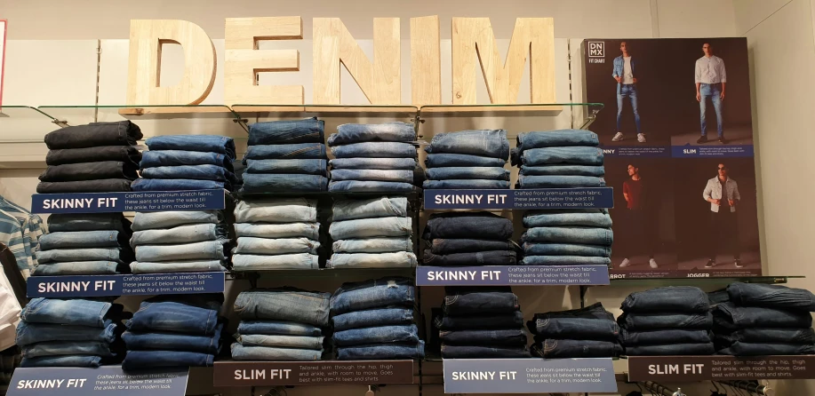 several stacks of jean pants and t - shirts displayed